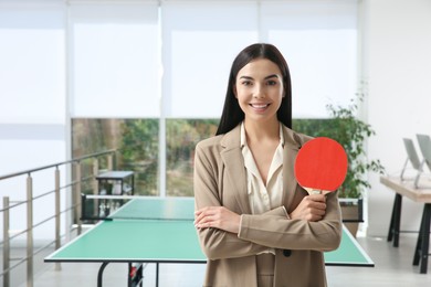Photo of Business woman with tennis racket near ping pong table in office. Space for text