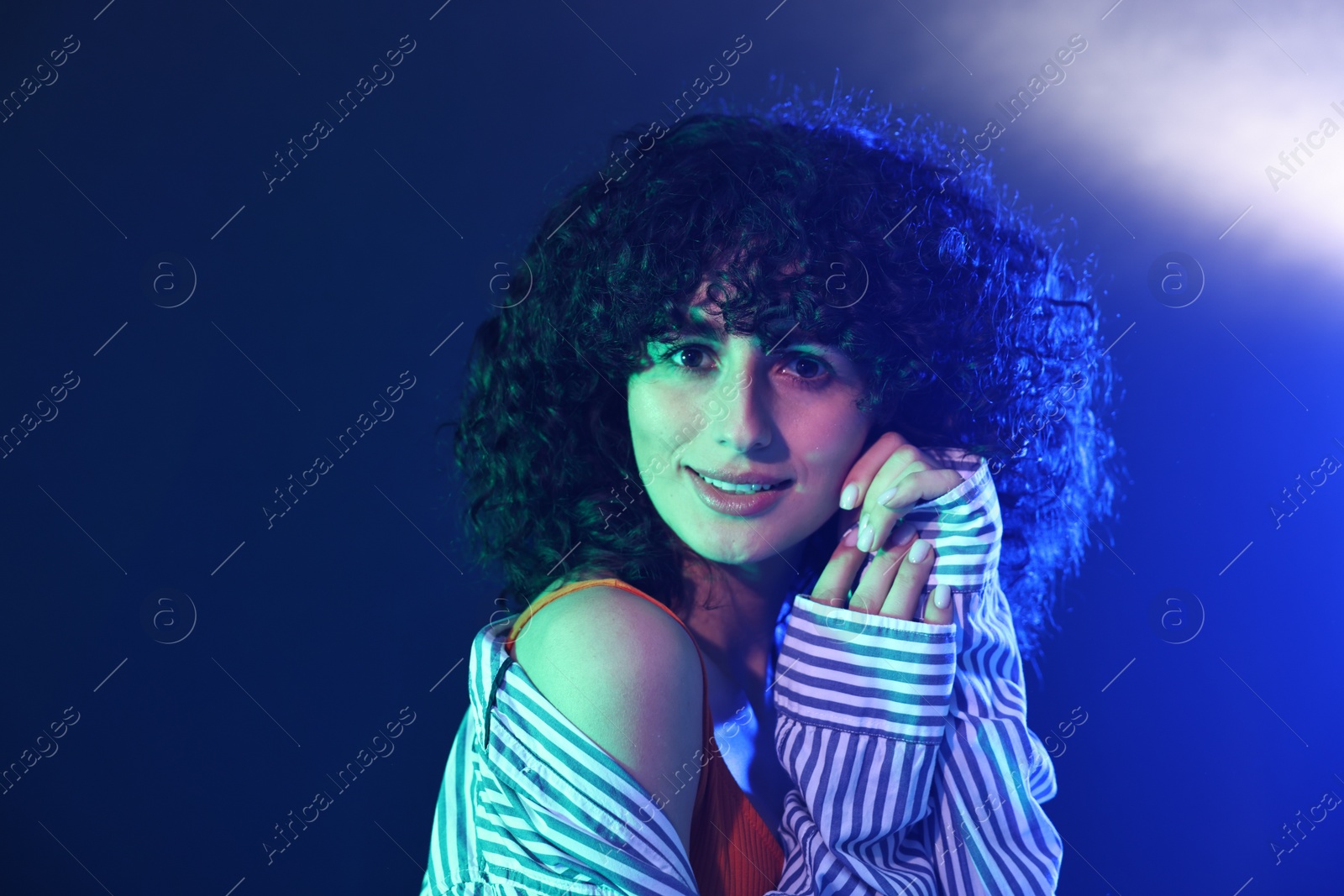 Photo of Beautiful young woman posing on color background in neon lights. Space for text