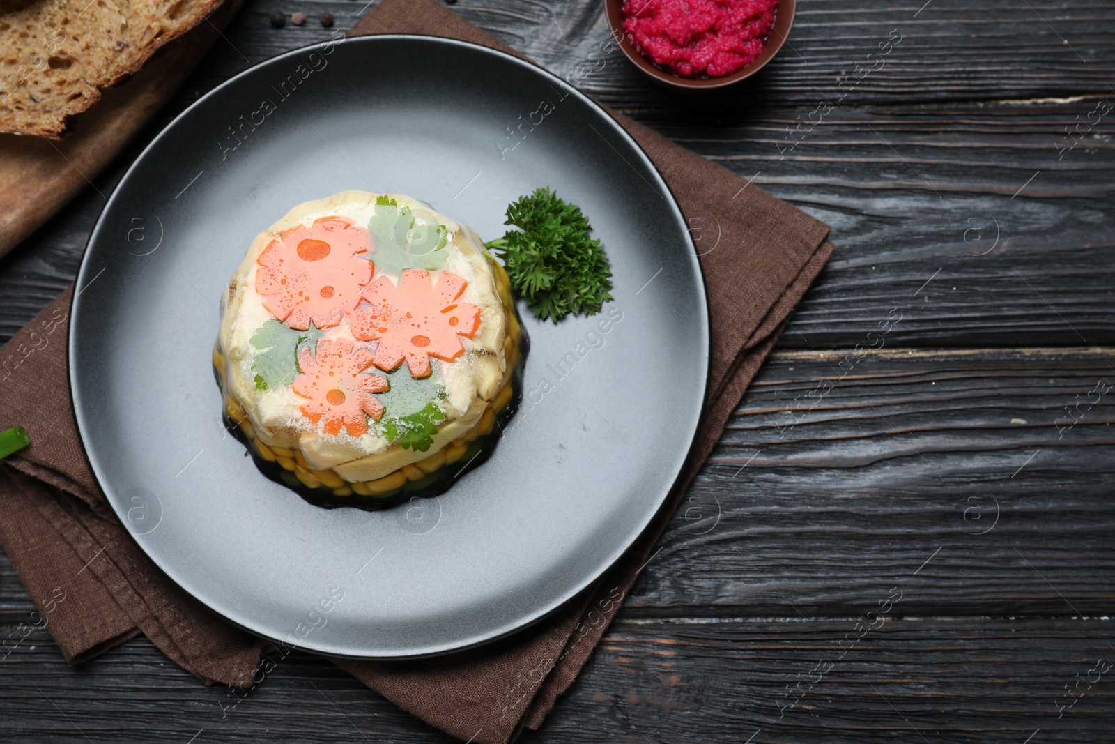 Photo of Delicious homemade chicken aspic served on black wooden table, flat lay