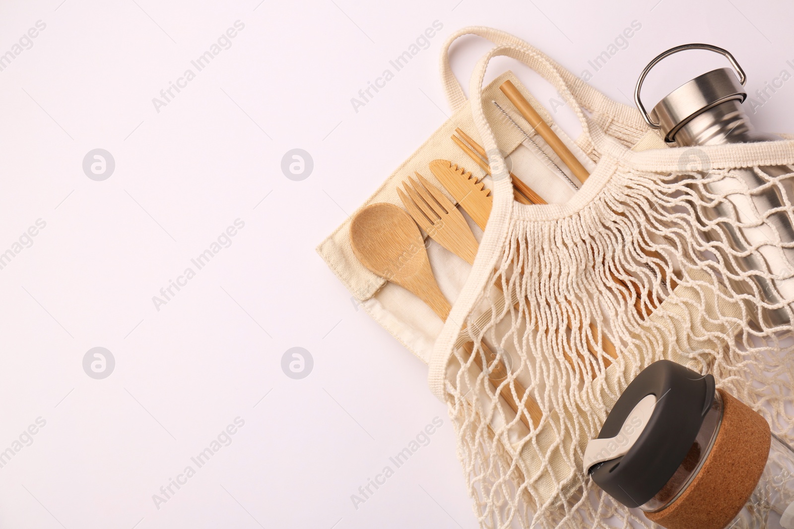 Photo of Fishnet bag with different items on white background, top view and space for text. Conscious consumption