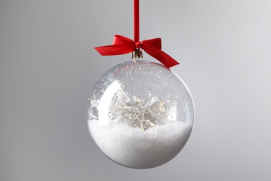 Photo of Decorative snow globe hanging on grey background, closeup