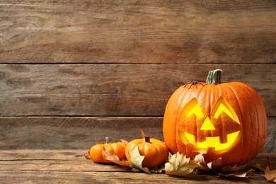 Composition with scary jack o'lantern pumpkin on wooden background, space for text. Halloween decor