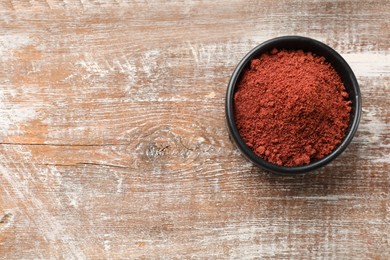 Photo of Cranberry powder in bowl on wooden table, top view. Space for text