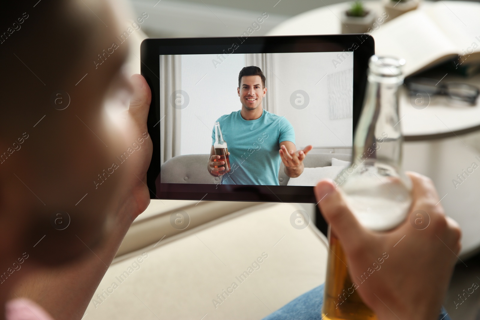 Photo of Friends drinking beer while communicating through online video conference at home. Social distancing during coronavirus pandemic