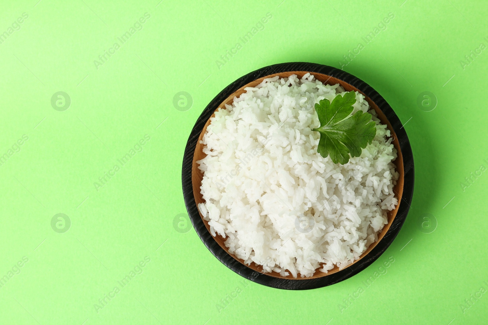 Photo of Bowl of boiled rice on color background, top view with space for text