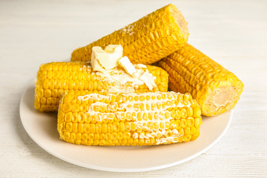 Photo of Delicious boiled corn with butter on white wooden table