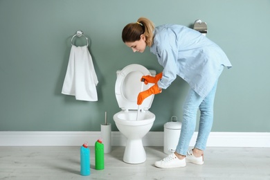 Woman cleaning toilet bowl in bathroom