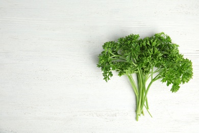 Photo of Bunch of fresh green parsley on wooden background, top view. Space for text