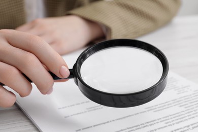 Photo of Woman looking at document through magnifier at table, closeup. Searching concept