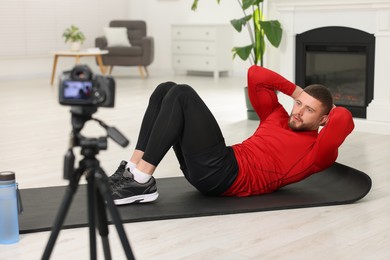 Photo of Trainer recording workout on camera at home