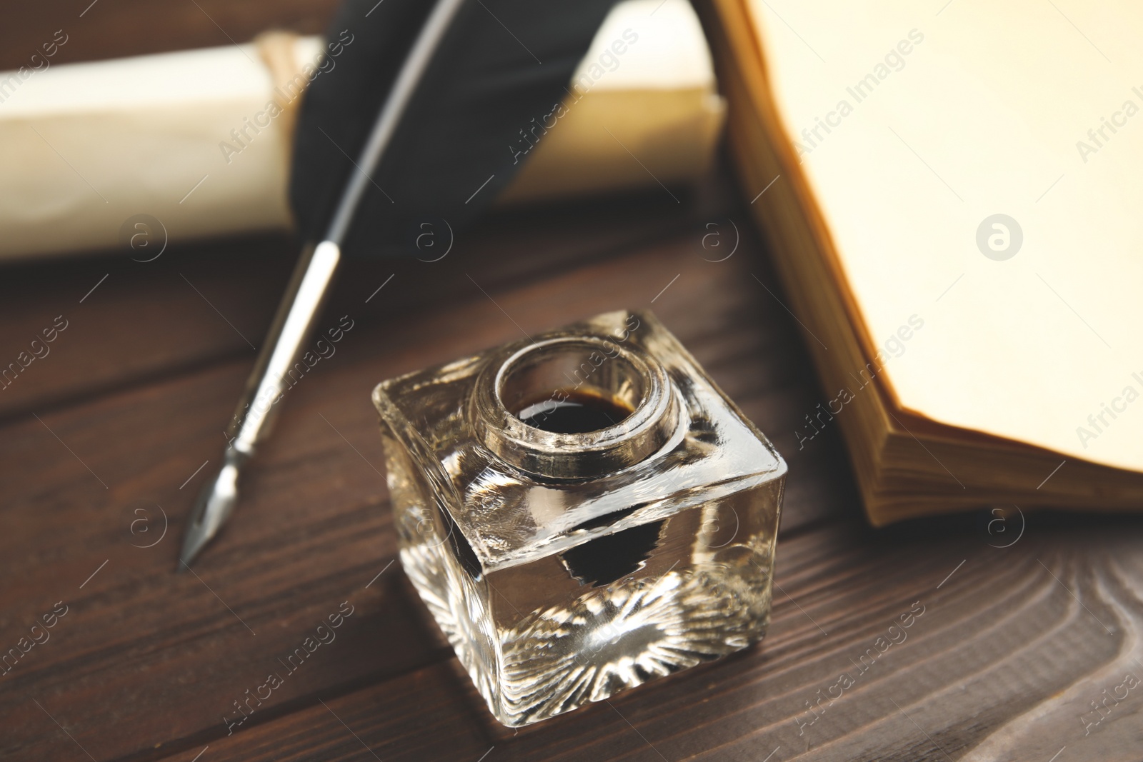 Photo of Feather pen, inkwell and paper on wooden table
