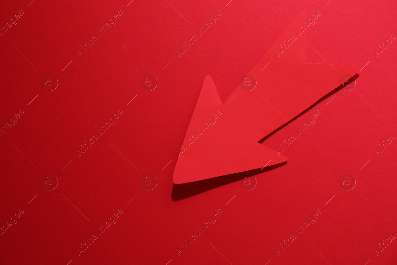 Photo of One paper arrow on red background, top view. Space for text