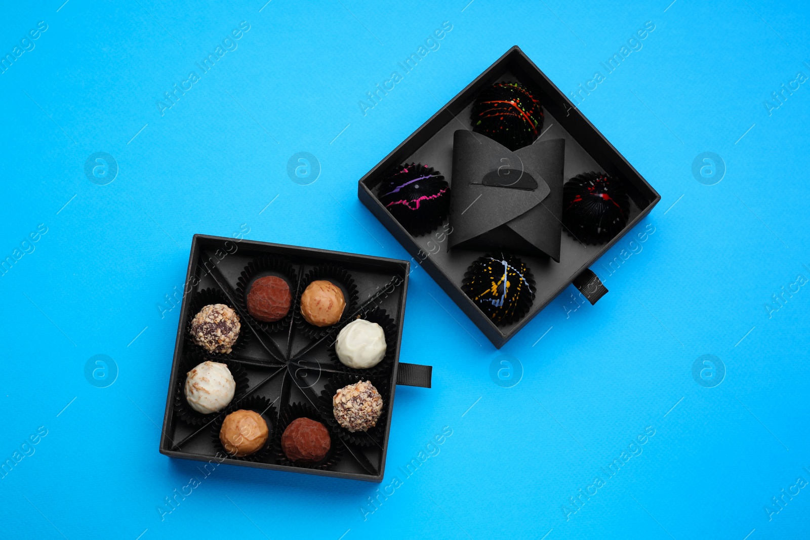 Photo of Boxes of tasty chocolate candies on blue background, flat lay