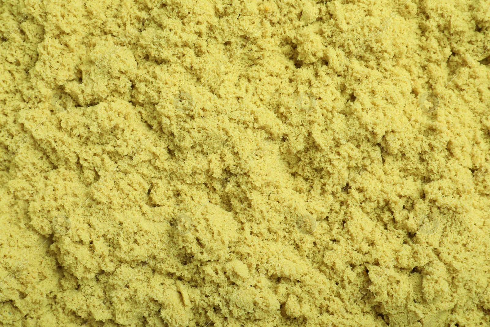 Photo of Yellow kinetic sand as background, closeup view