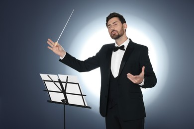 Professional conductor with baton and note stand on grey background