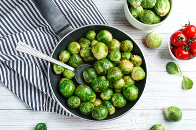 Photo of Roasted Brussels sprouts in pan on white wooden table, flat lay