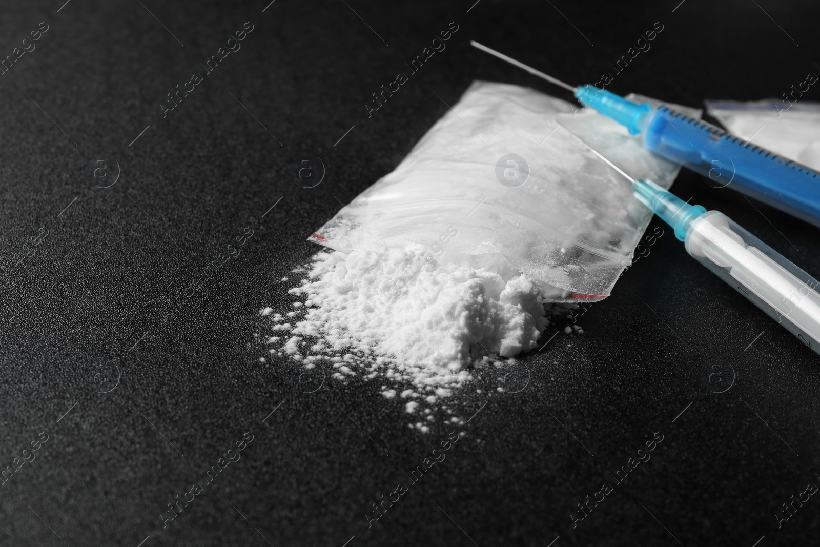 Photo of Cocaine in plastic bag and syringes on dark background. Space for text