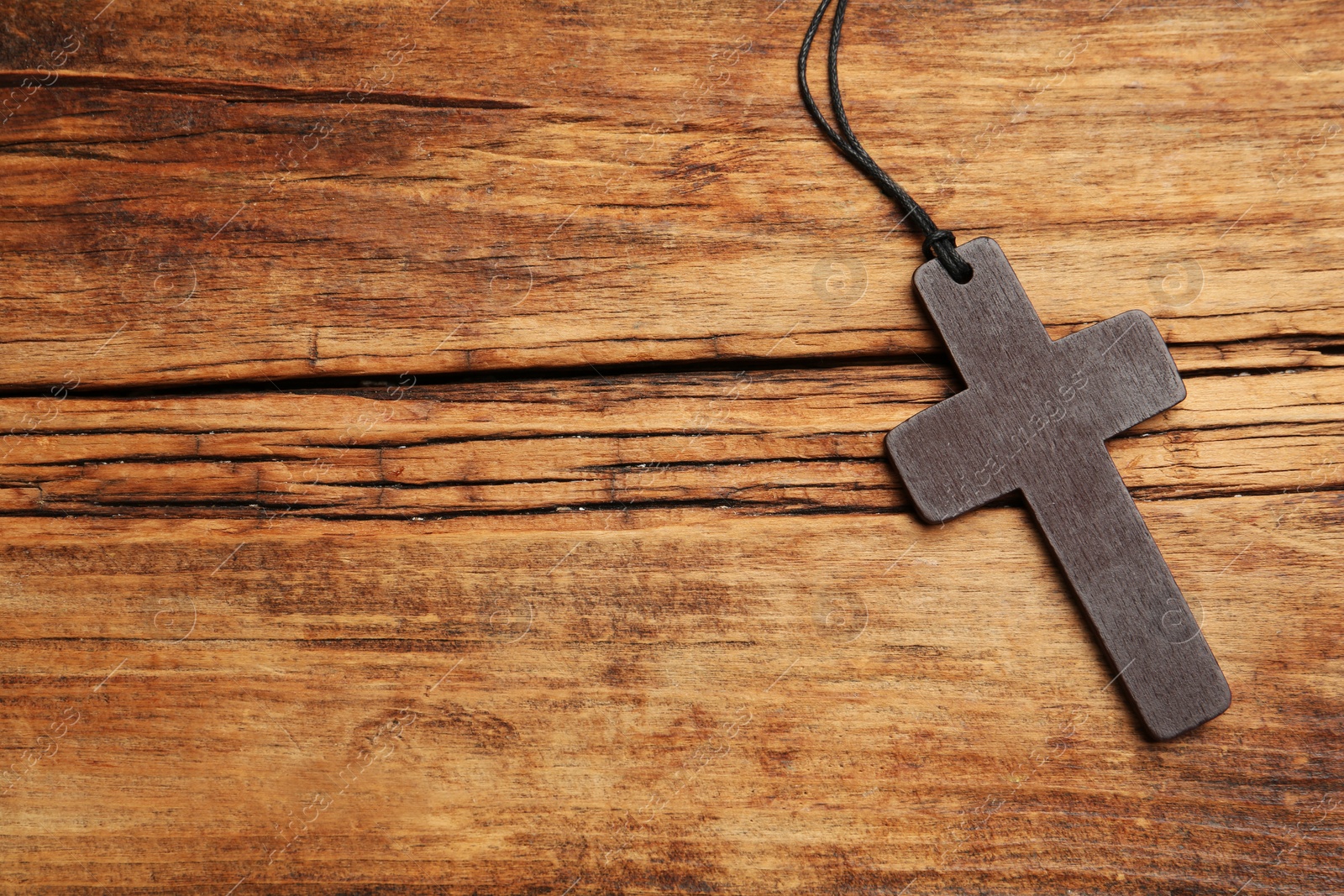 Photo of Christian cross on wooden table, top view. Space for text