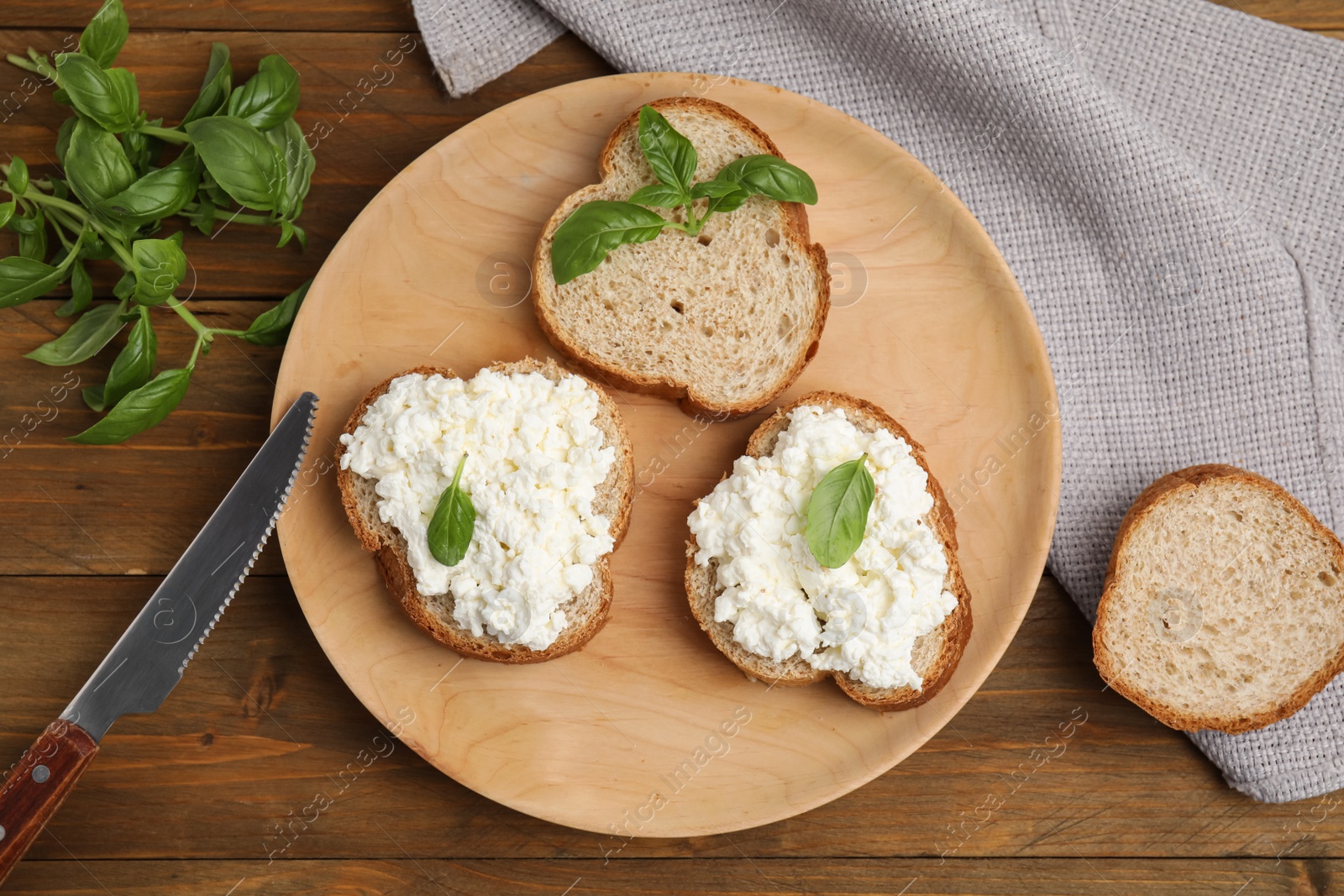 Photo of Bread with cottage cheese and basil on wooden table, flat lay