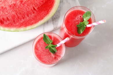 Tasty summer watermelon drink in glasses and board with sliced fruit on table, top view