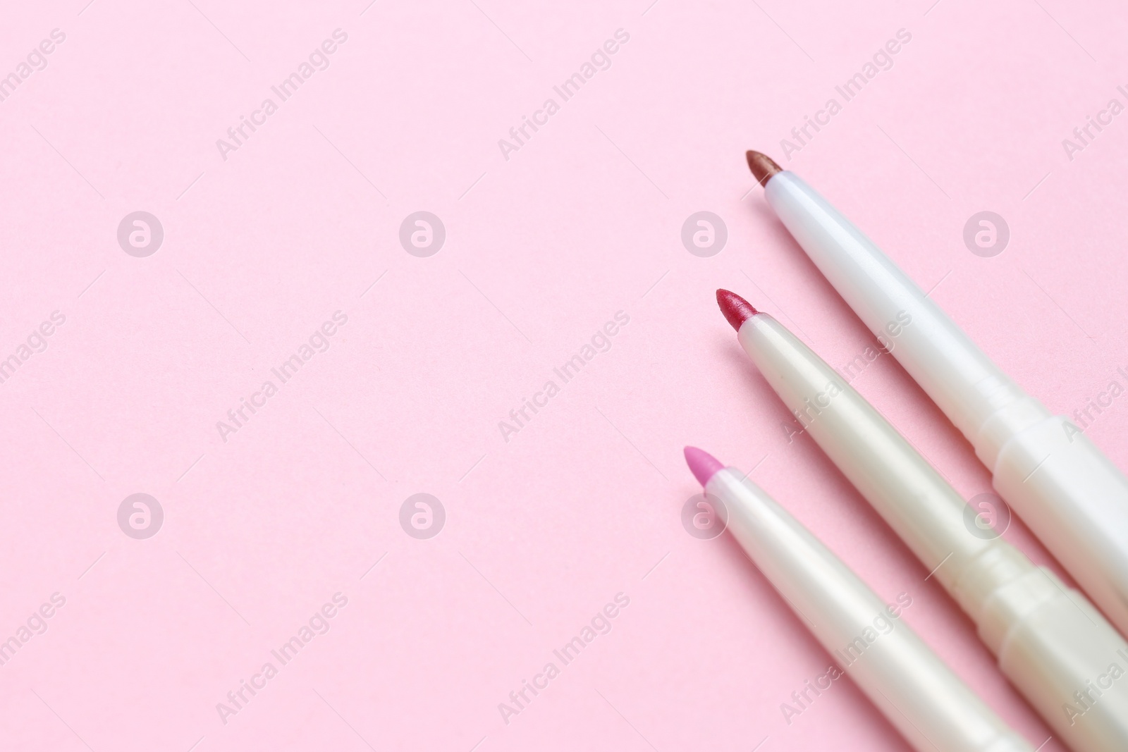 Photo of Lip pencils on pink background, flat lay with space for text. Cosmetic product