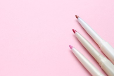 Photo of Lip pencils on pink background, flat lay with space for text. Cosmetic product