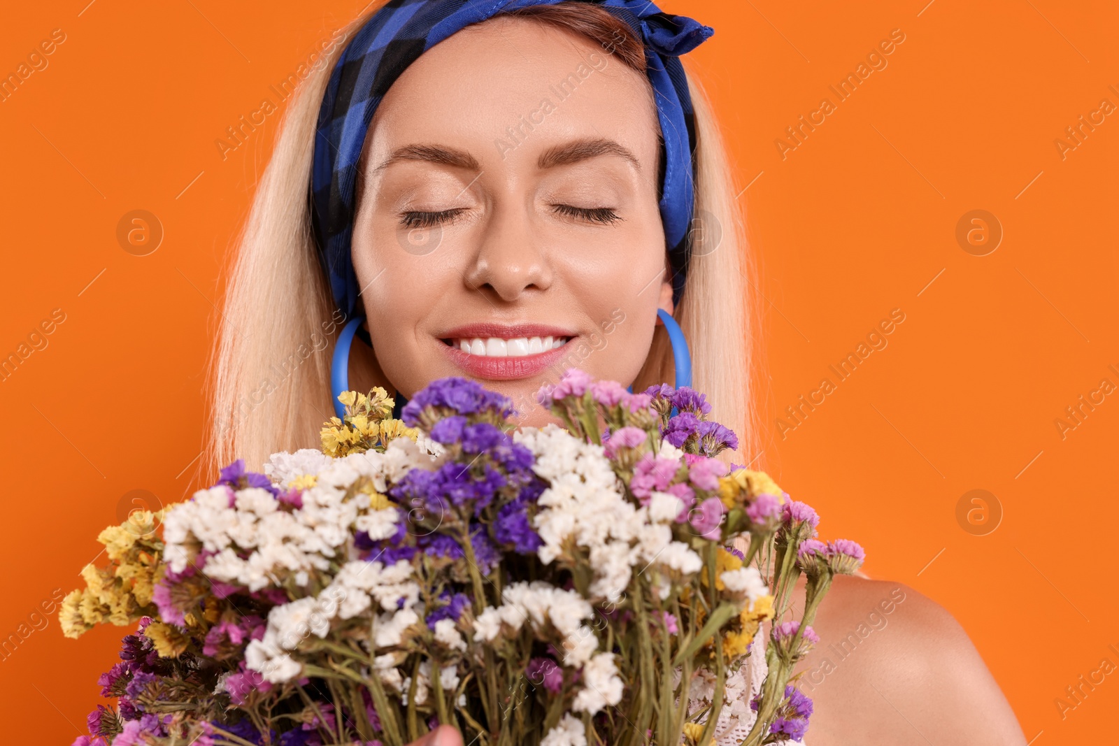 Photo of Happy hippie woman with bouquet of flowers on orange background