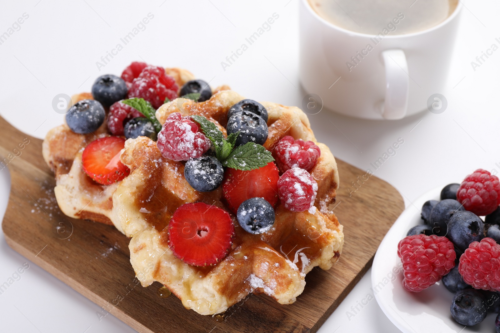 Photo of Delicious Belgian waffles with fresh berries on white table, closeup