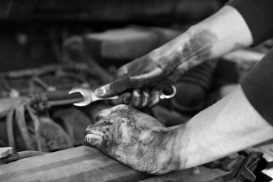 Photo of Dirty mechanic fixing car, closeup of hands. Black and white effect