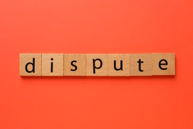 Photo of Word Dispute made with wooden cubes on red background, top view