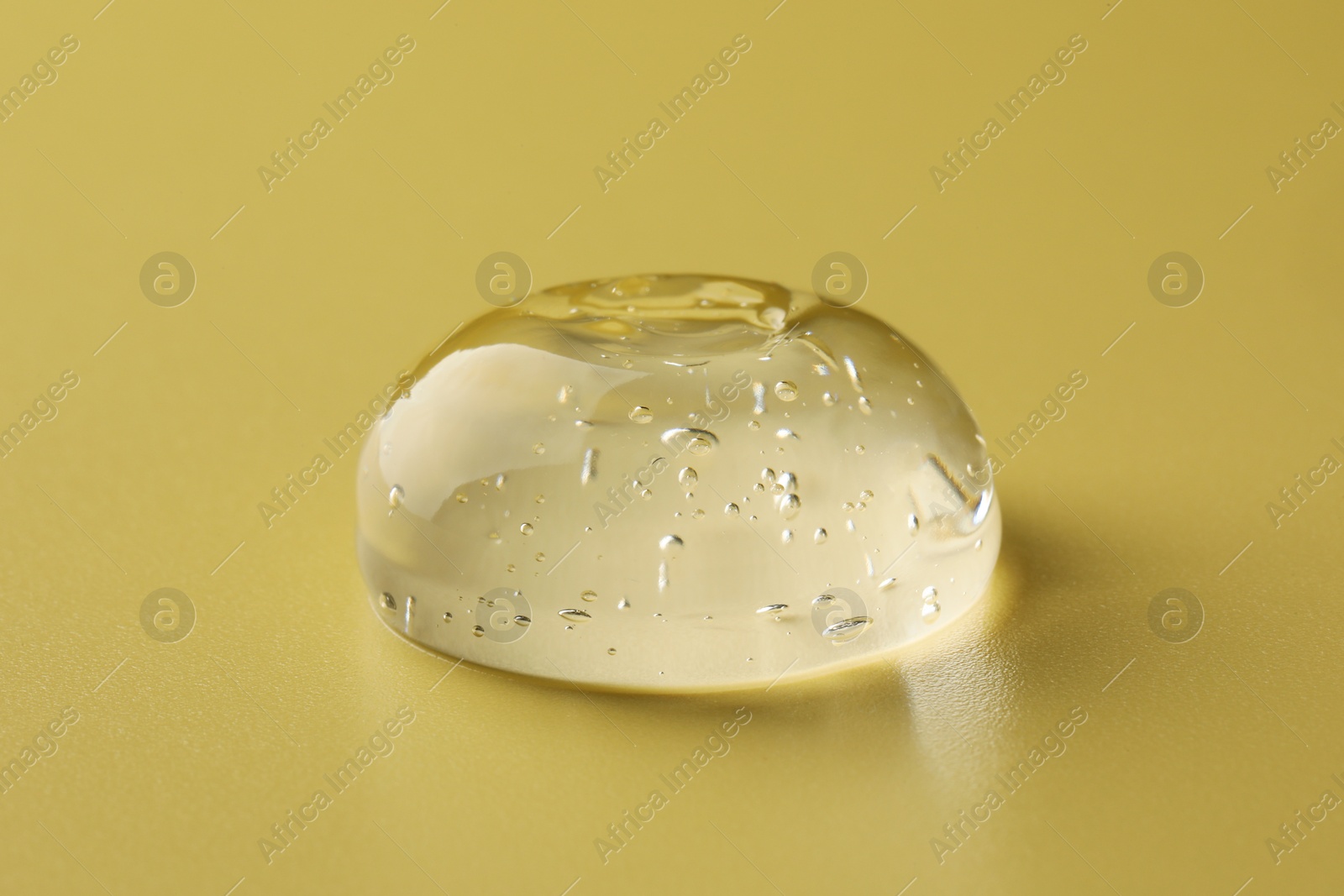 Photo of Sample of clear cosmetic gel on yellow background, closeup