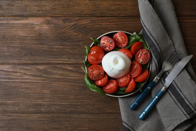 Delicious burrata cheese with tomatoes and basil served on wooden table, flat lay. Space for text