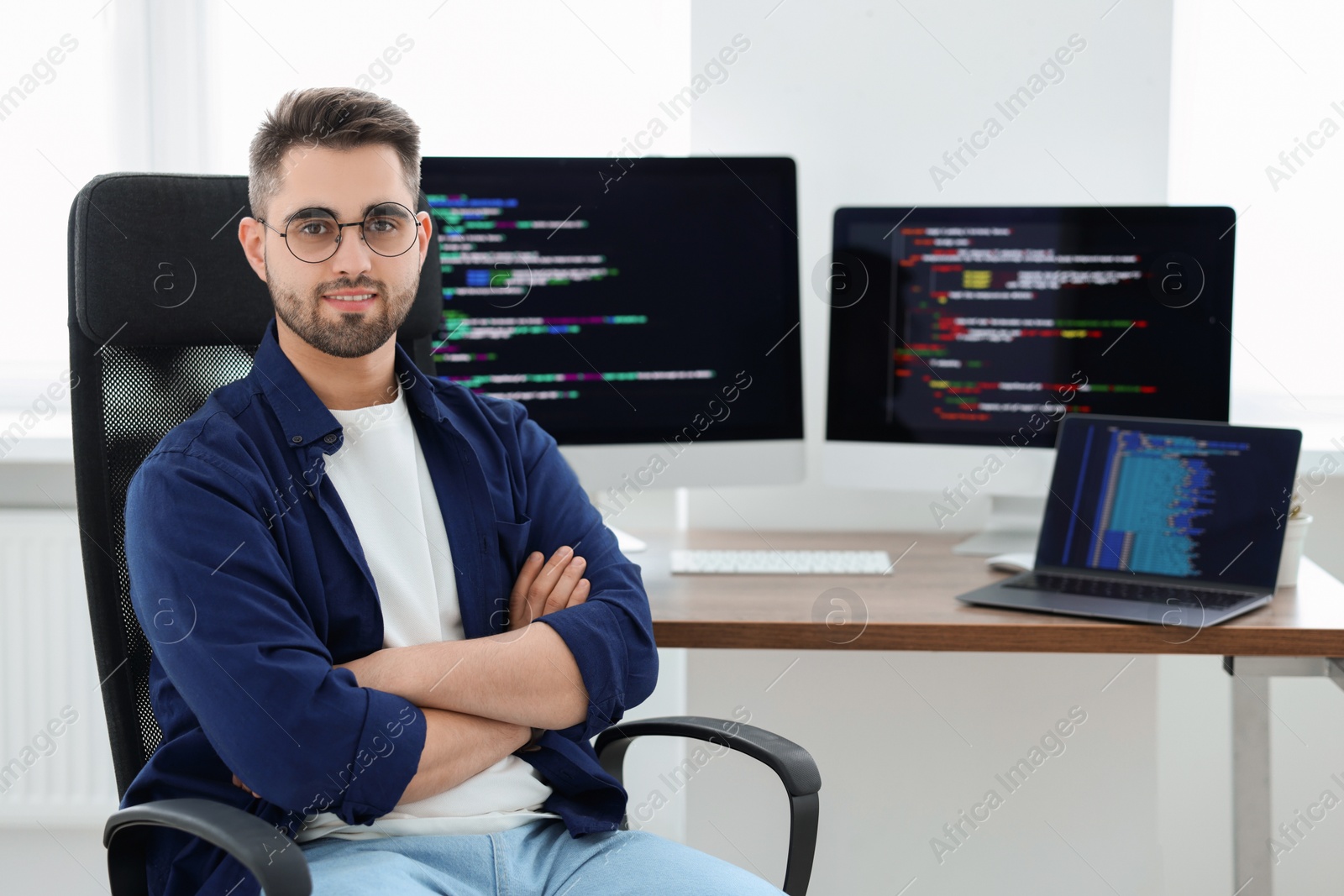 Photo of Happy young programmer working at desk in office