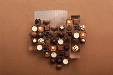 Photo of Heart made with delicious chocolate candies on brown background, top view