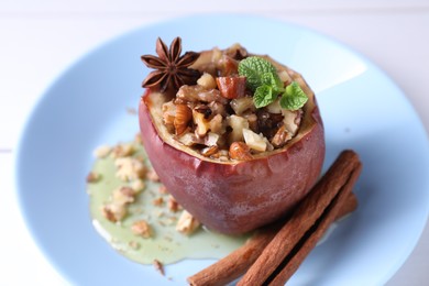 Photo of Tasty baked apple with nuts, honey, spices and mint on white table, closeup