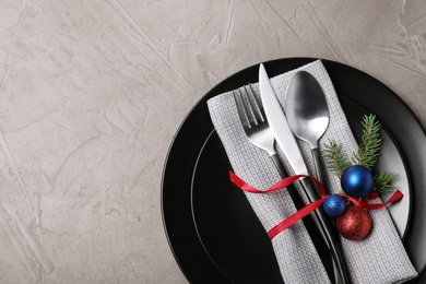 Photo of Plates, cutlery, napkin and Christmas decor on grey background, top view. Space for text