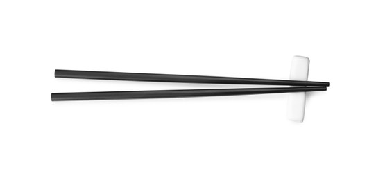 Photo of Pair of black chopsticks with rest isolated on white, top view