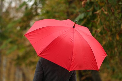 Photo of Woman with red umbrella in autumn park, back view