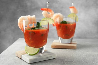 Photo of Tasty shrimp cocktail with sauce in glasses and lime on light grey table