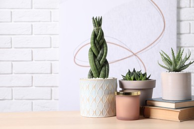 Photo of Beautiful Sansevieria, Aloe and Haworthia in pots with decor on wooden table against white brick wall, space for text. Different house plants