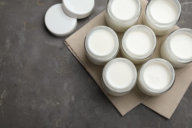 Tasty yogurt in glass jars on grey table, flat lay. Space for text
