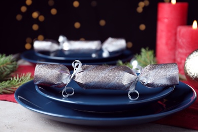 Photo of Bright silver Christmas cracker on table indoors