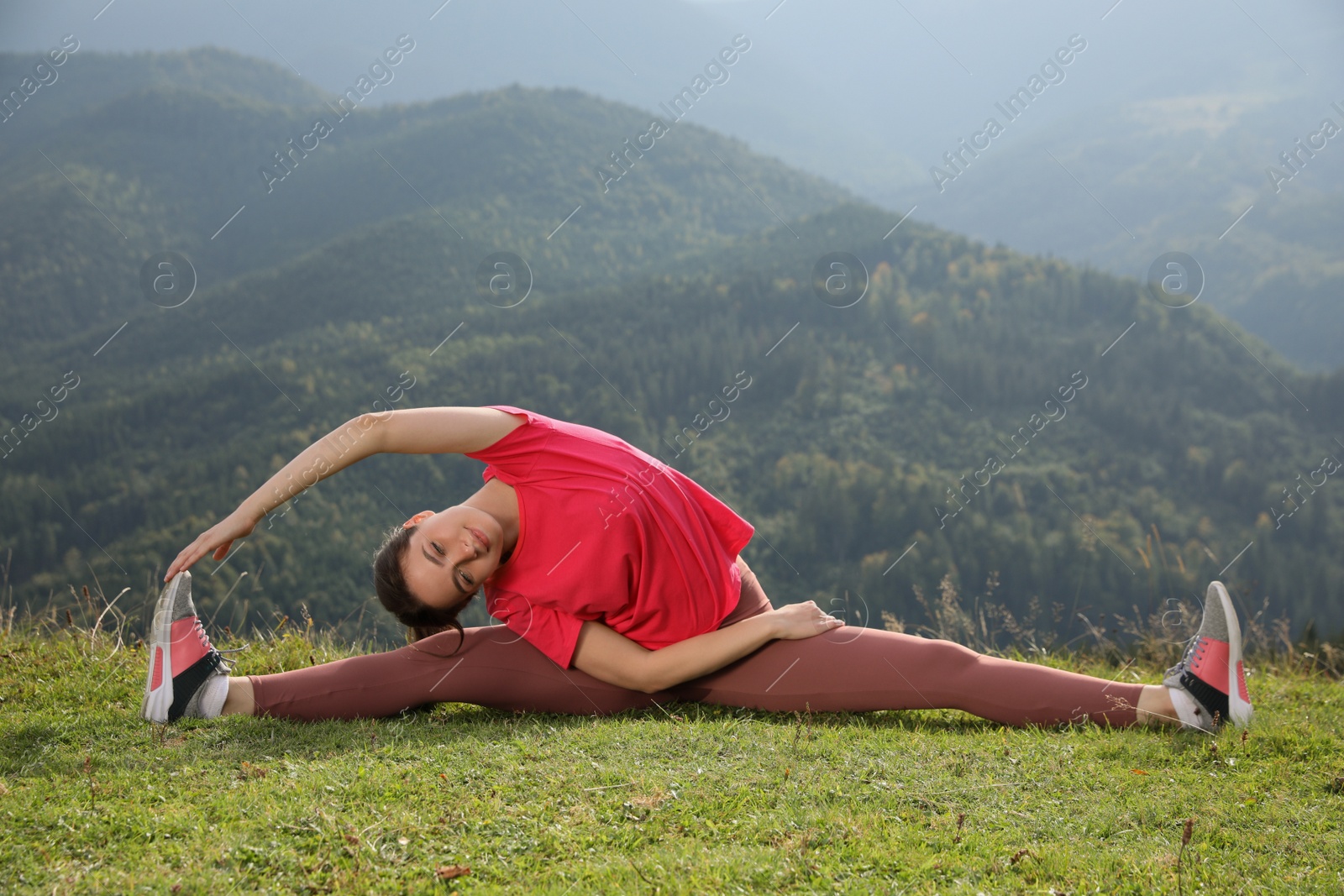 Photo of Young woman doing morning exercise in mountains