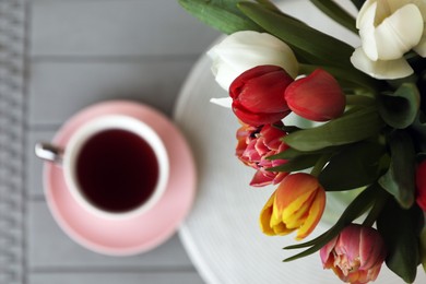 Photo of Beautiful bouquet of colorful tulips and cup with drink on grey table, top view. Space for text