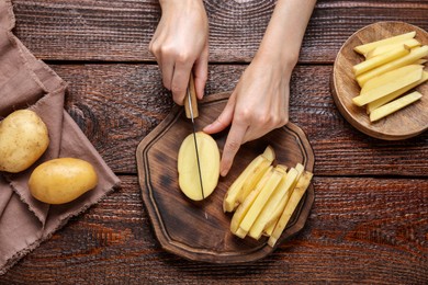 Photo of Woman cut potatoes at wooden table, top view