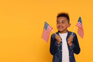 Photo of 4th of July - Independence Day of USA. Happy boy with American flags on yellow background, space for text