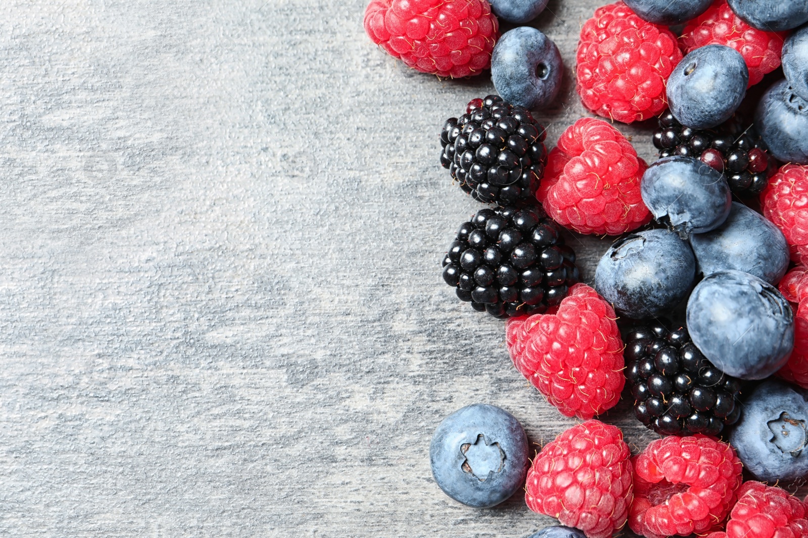 Photo of Raspberries, blackberries and blueberries on table, top view