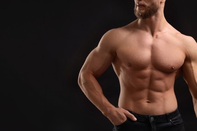 Photo of Muscular man showing abs on black background, closeup and space for text. Sexy body