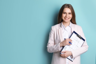 Beautiful real estate agent with clipboard on color background