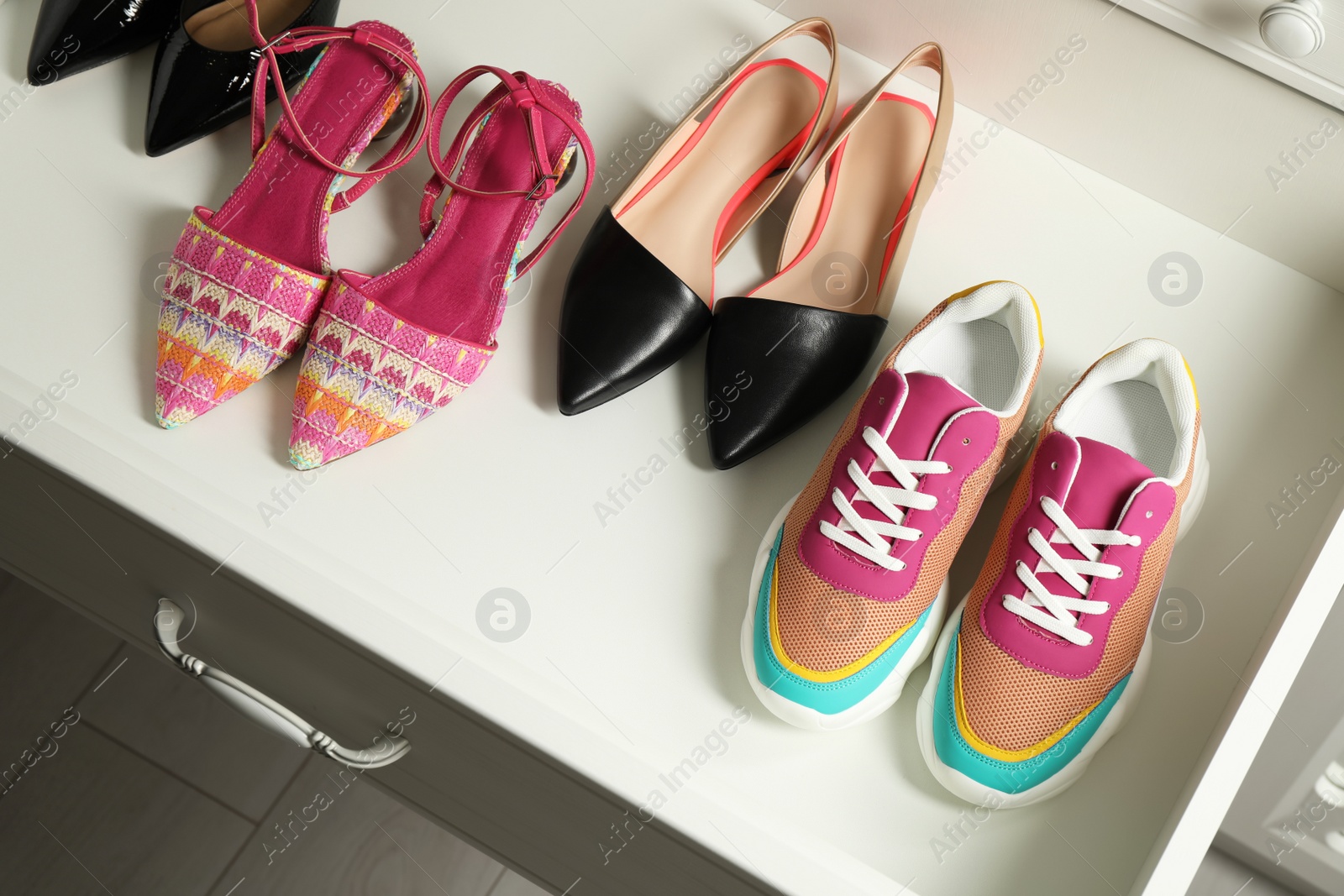 Photo of Different women's shoes in open drawer. Footwear storage